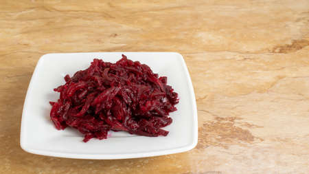 Bowl of grated red beet on table in white ceramicの写真素材