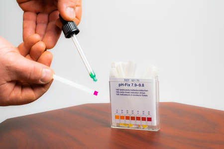 ph testing. alkaline pH test strips. dropper in handの写真素材