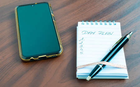 plan of the day notebook and pen and a phone with a smartphoneの写真素材