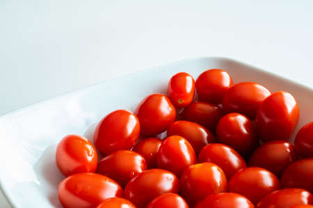 tiny red tomatoes on a white potの写真素材