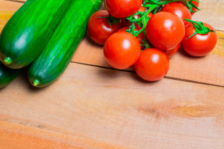 red tomatoes and green cucumber on wooden planks.の写真素材