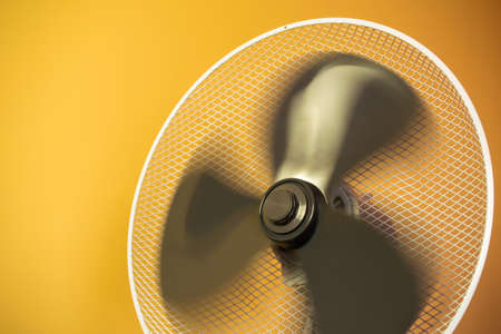 working electric fan, windmill on the background of a yellow wall