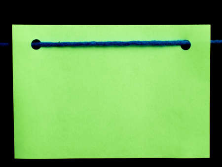 green blank note card with blue string on black background