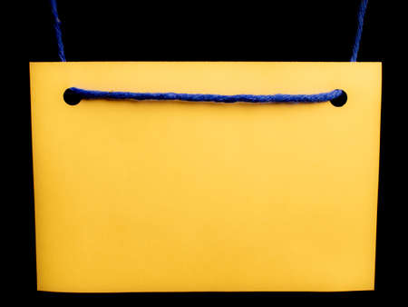 yellow blank note card with blue string over black backgroundの写真素材