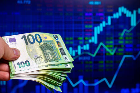 hundreds of euro banknotes on the background of a stock chartの写真素材