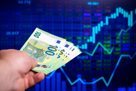 hundreds of euro banknotes on the background of a stock chartの写真素材