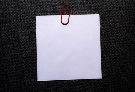 white blank note pinned to a notice board with a paper clip.
