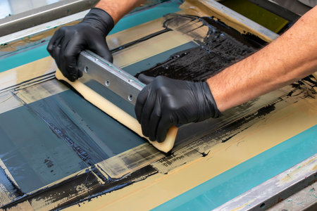 hand made screen printing, squeezing the paint with a squeegee