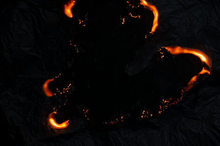 burning paper, glowing edge of paper on a black backgroundの写真素材