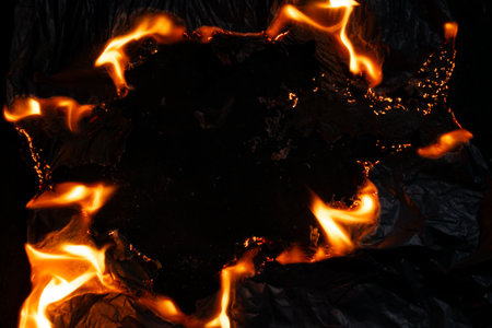 burning paper, glowing edge of paper on a black backgroundの写真素材