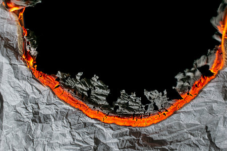 burning paper, glowing edge of paper on a black backgroundの写真素材