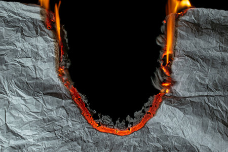burning paper, glowing edge of paper on a black backgroundの写真素材