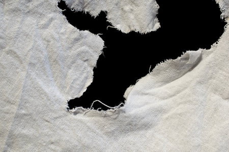 torn old white rag with holes on a black backgroundの写真素材