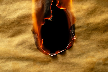 burning old brown paper, glowing edge of paper on a black backgroundの写真素材