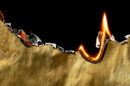 burning old brown paper, glowing edge of paper on a black backgroundの写真素材
