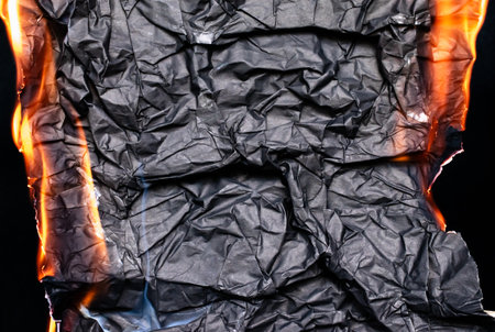 burning back paper, glowing edge of paper on a black backgroundの写真素材