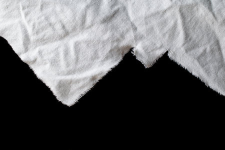 torn old white rag with holes on a black backgroundの写真素材