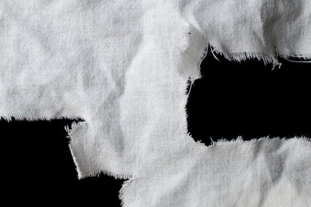 torn old white rag with holes on a black backgroundの写真素材