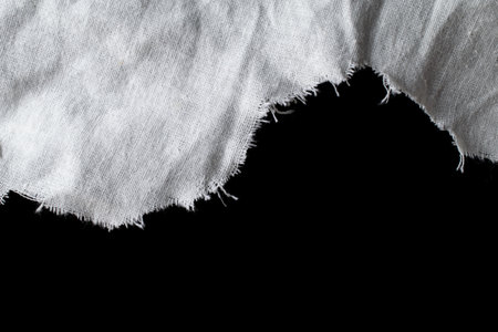 torn old white rag with holes on a black backgroundの写真素材