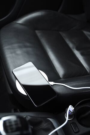 Mobile phone, smartphone charge battery, wireless charging in the car plug close up