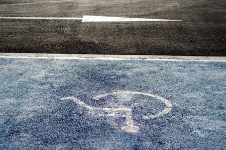 International handicapped symbol painted in bright blue on a shopping center parking space.の写真素材