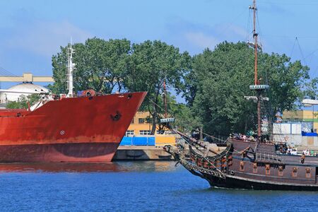 Cargo ship and pirate touristic ship passing together on the port channelの写真素材