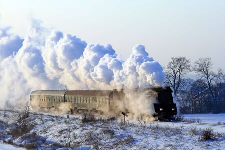 Vintage steam train passing through snowy countrysideの写真素材