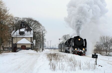 Old retro steam train starting from the station during wintertimeの写真素材