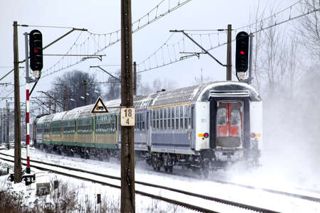 Passenger train passes the snowy line during wintertime in Polandの写真素材
