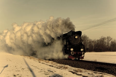 Vintage steam train puffing through countryside during wintertime