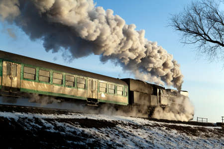 Vintage steam train puffing through countryside during wintertimeの写真素材