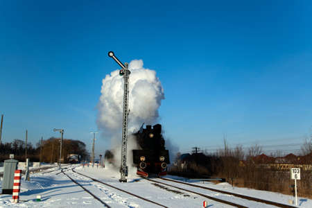 Vintage steam train puffing through countryside during wintertimeの写真素材