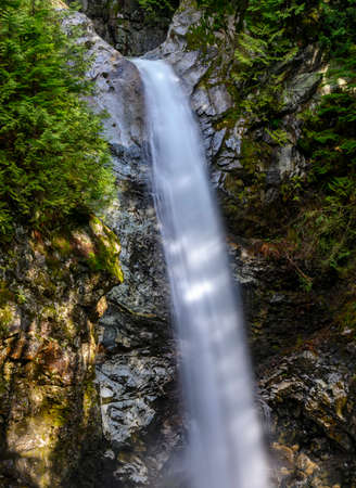Beautiful waterfall in Spring. Long exposure, silky texture. Blurred motion. Green foliage and rocks surround the waterfall. Close up of the cliff and the top of the fallの写真素材
