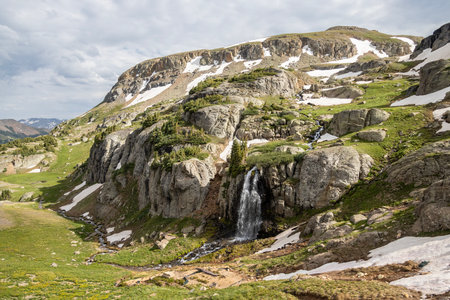 Beautiful scenery with waterfall and mountains in the background. Some snow on the glaciers still there in the Summerの写真素材