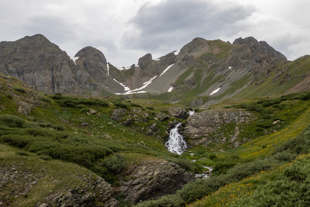 Beautiful scenery with waterfall and mountains in the background. Some snow on the glaciers still there in the Summerの写真素材