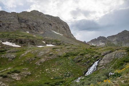 Beautiful scenery with waterfall and mountains in the background. Some snow on the glaciers still there in the Summerの写真素材