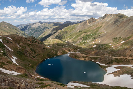 Beautiful mountain view with a clear, blue lake. Beautiful blue sky with clouds. Summer photo, but glaciers still have some snow left.の写真素材