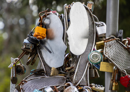 Various locks and metallic elements are creatively arranged at a public park, creating an...