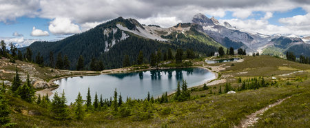 Breathtaking view of Elfin Lakes surrounded by dense trees. The scene showcases clear water reflecting the sky on a warm summer day.の写真素材