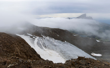 The breathtaking landscape showcases the snow-covered Black Tusk beneath a blanket of low-hanging clouds, with a striking mountain peak visible in the background, capturing the essence of natureâs beauty.の写真素材