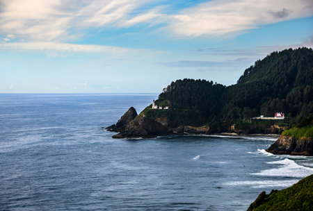 Waves crash against rocky cliffs along the Oregon coast, featuring a historic lighthouse perched...