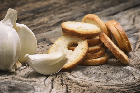 Mini rolls of baked bread and garlic isolated on wooden backgroundの写真素材