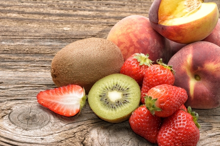 Kiwi , peach and strawberry on wooden backgroundの写真素材