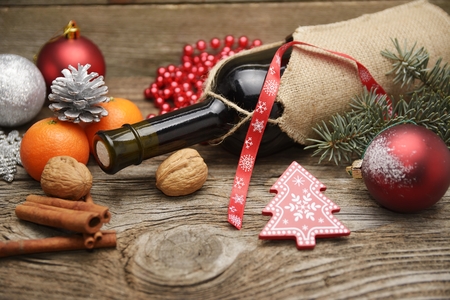 Red wine and Christmas ornaments on wooden table on wooden backgroundの写真素材
