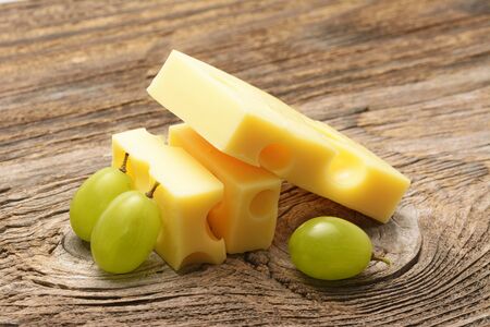 Piece of cheese and grape on wooden boardの写真素材