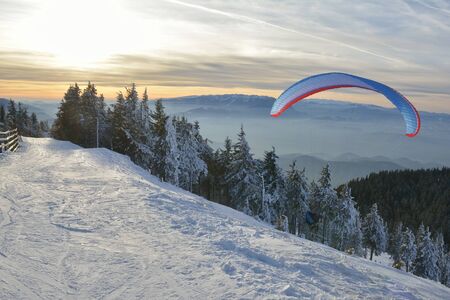 Paraglide silhouette over mountain peaks.の写真素材