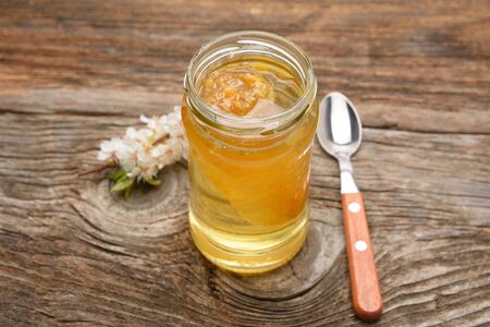 Glass pot full of honey on rustic wooden backgroundの写真素材