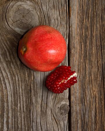 Juicy pomegranate and red grains on wooden backgroundの写真素材