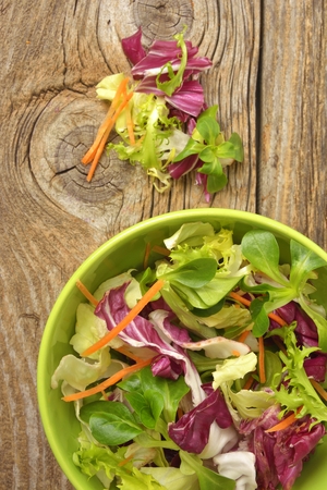 Fresh mixed green salad in bowl on wooden table close upの写真素材