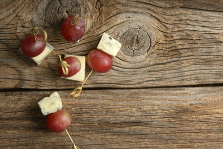 pieces of blue cheese and red grapes on a wooden tableの写真素材
